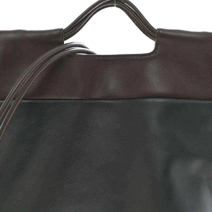 Close-up of black leather tote bag top edge and handle openings.