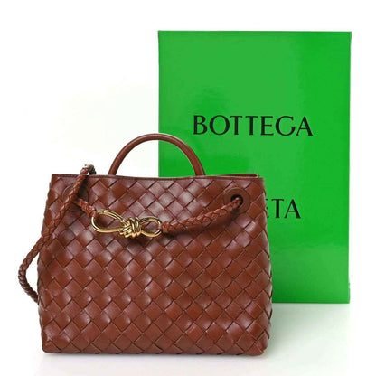 Small woven leather bag in Sapele brown with gold clasp, top handle, and drawstring