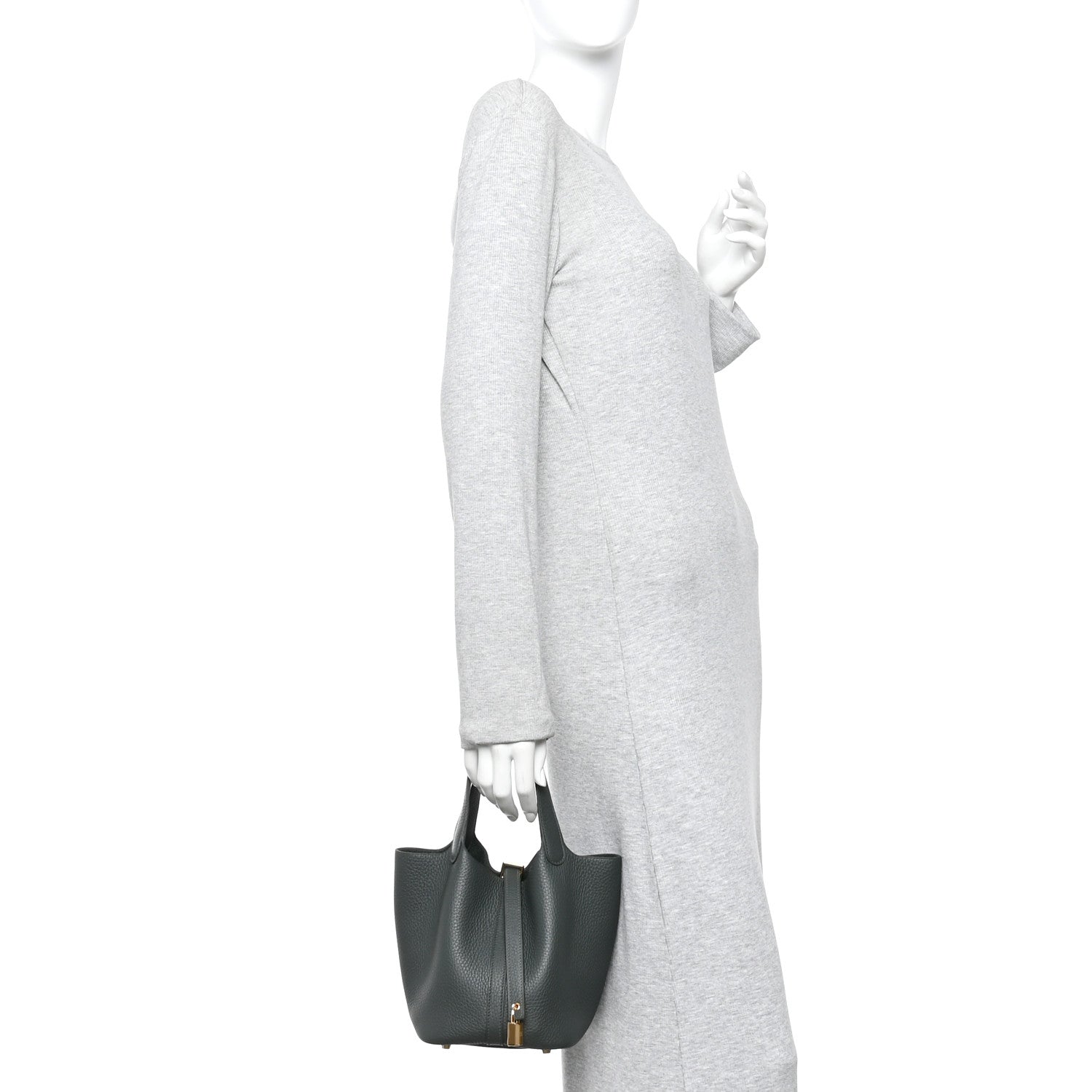 Mini tote bag held at side, textured dark green leather with small gold lock.
