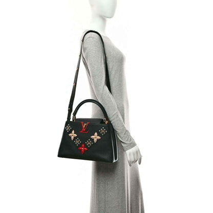 Black Louis Vuitton handbag with gold trim, short handles, and floral charm details