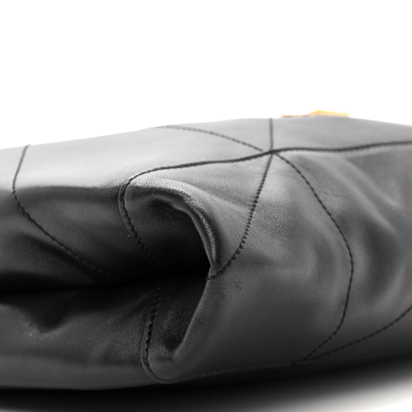 Black quilted leather drawstring bag with gathered top and stitched seams close-up