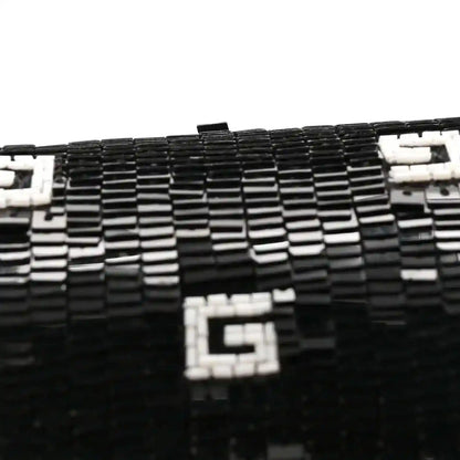 Black mini top handle bag close-up with white square GG motif on textured surface