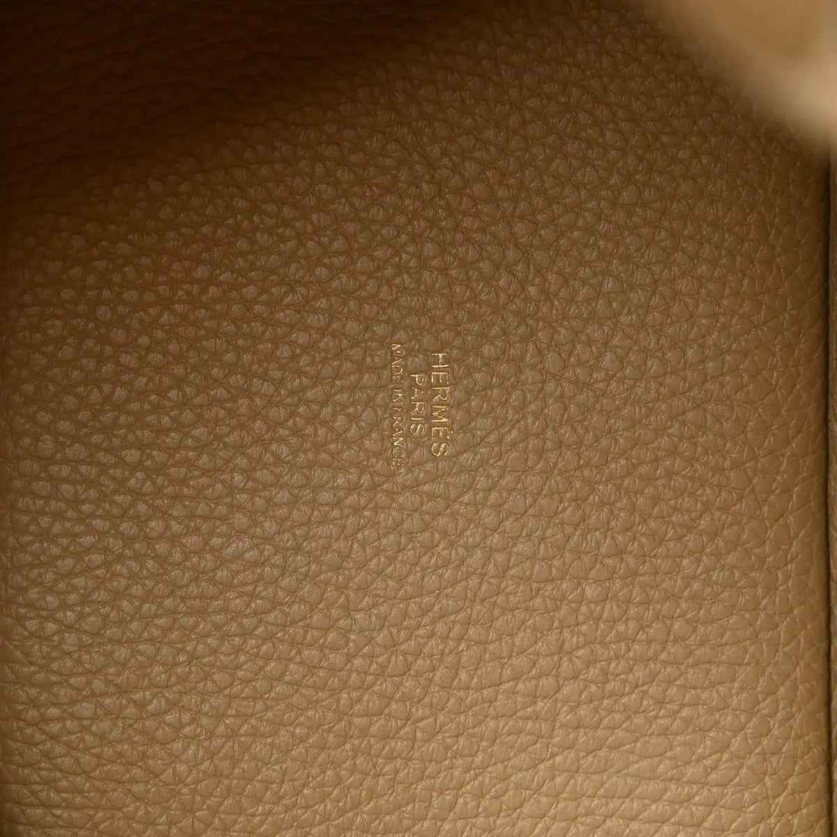 Beige grained leather lining with embossed HERMES logo on interior panel.
