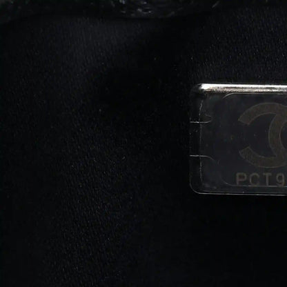 Handbag logo tag detail with metallic hardware on dark quilted caviar leather