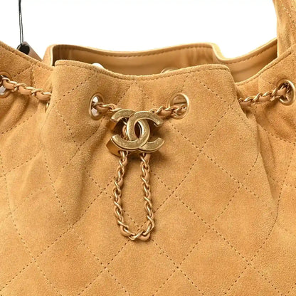 Chanel quilted beige suede handbag with CC charm, chain pull, and aged gold hardware