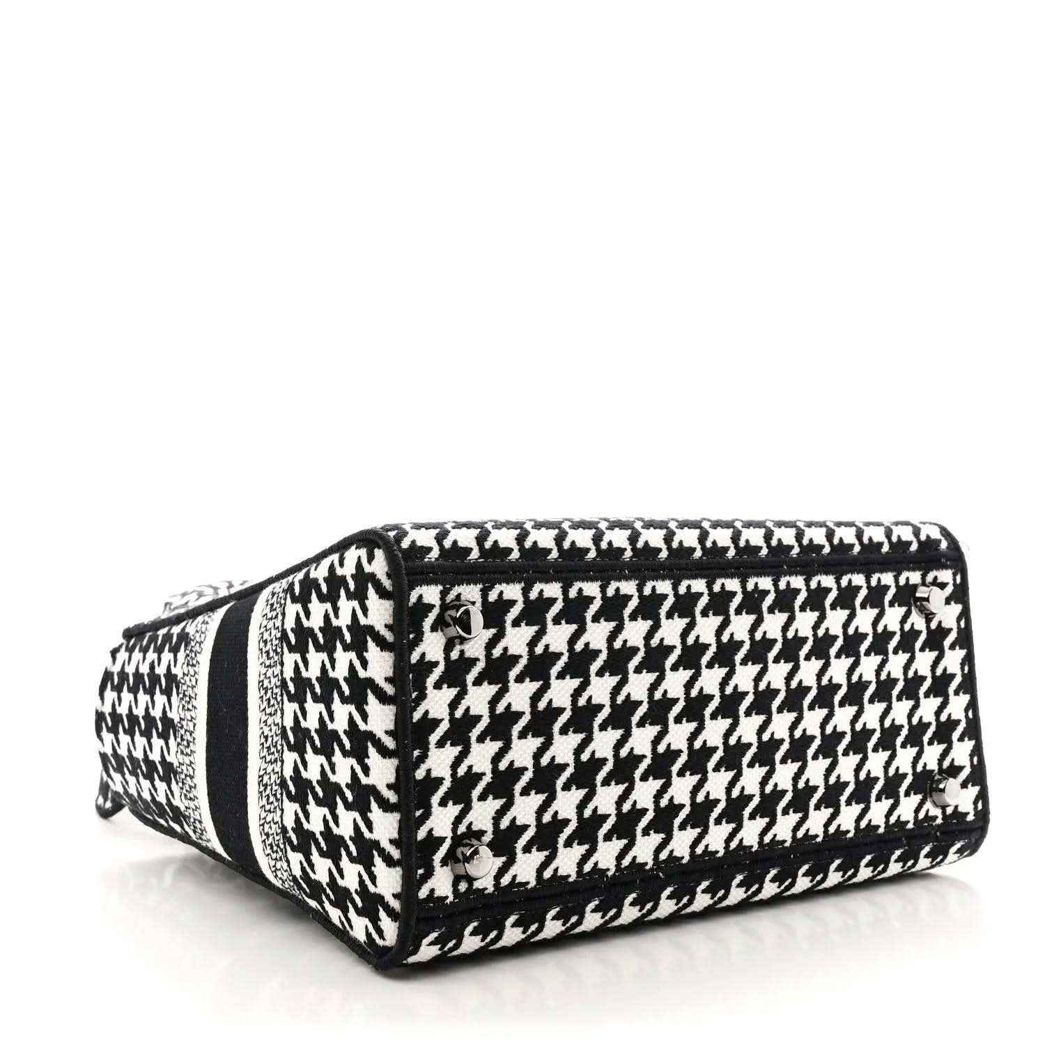 Black-and-white houndstooth canvas duffel-style bag with black trim and top handle