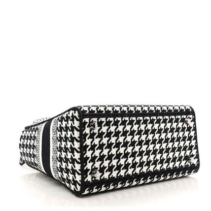 Black-and-white houndstooth canvas duffel-style bag with black trim and top handle