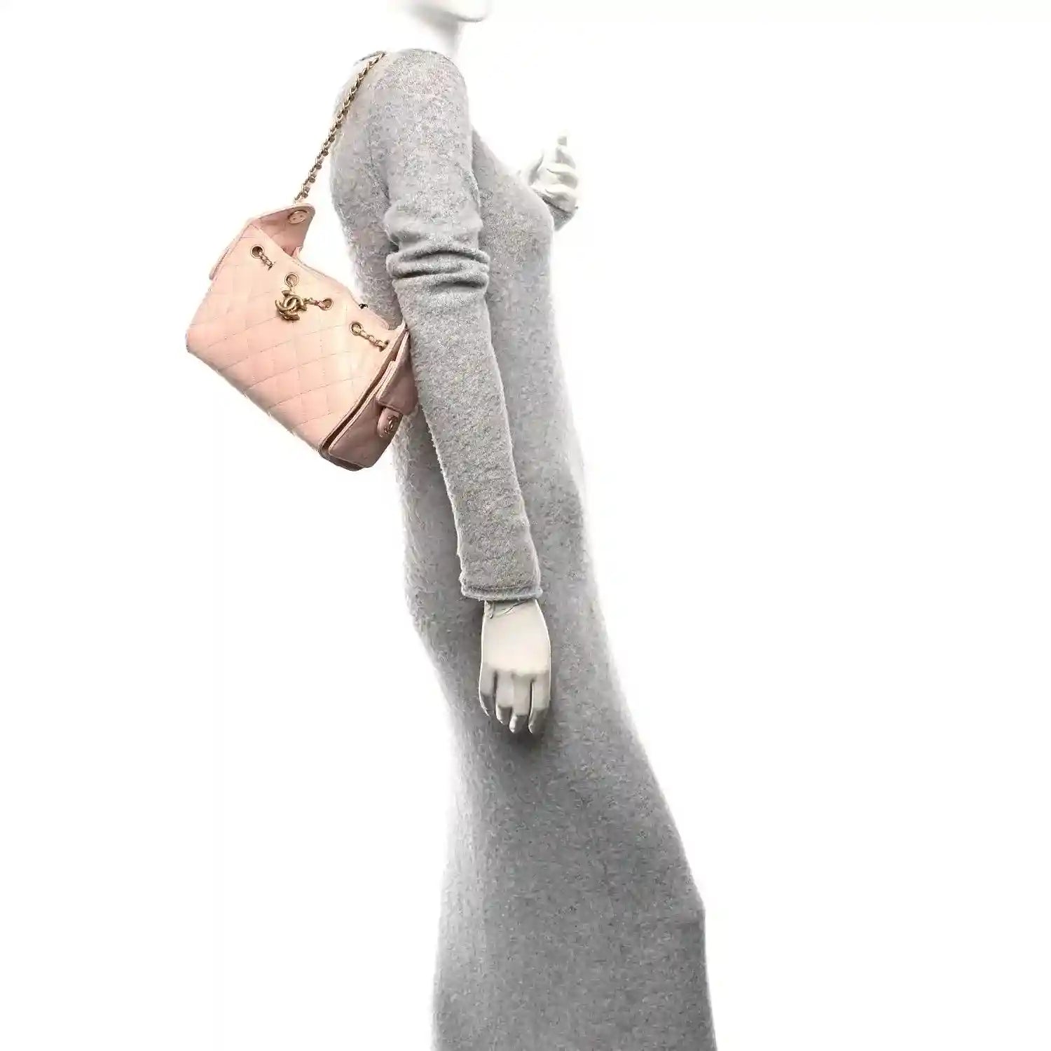 Light pink mini handbag on a chain shoulder strap, held at the side