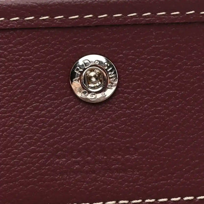 Round silver snap button on burgundy leather flap, with embossed details