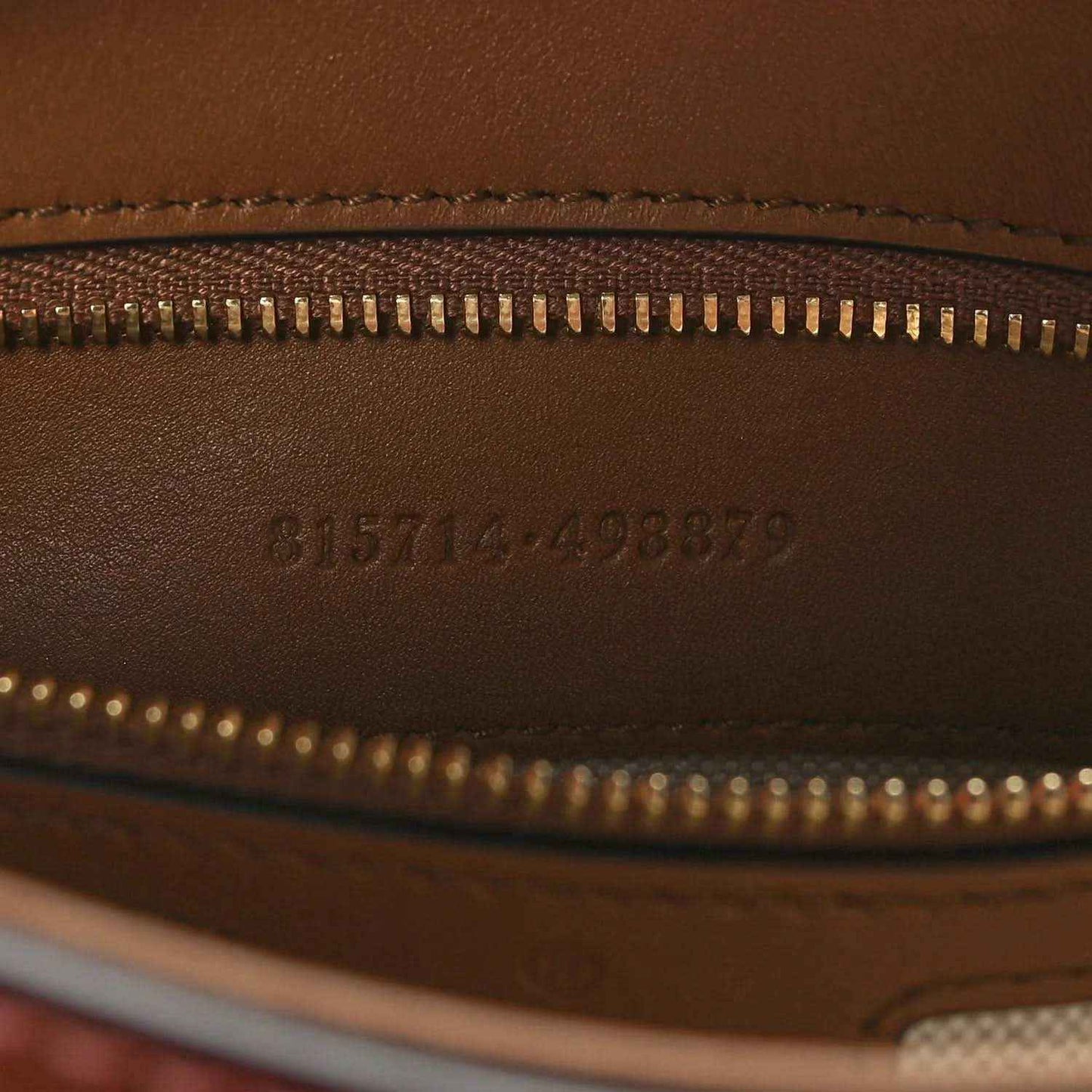 Brown leather exterior with gold zipper and embossed serial code