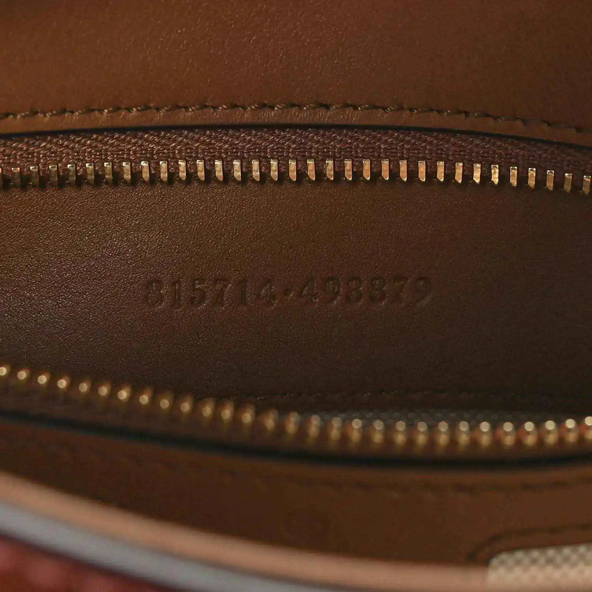 Brown leather exterior with gold zipper and embossed serial code