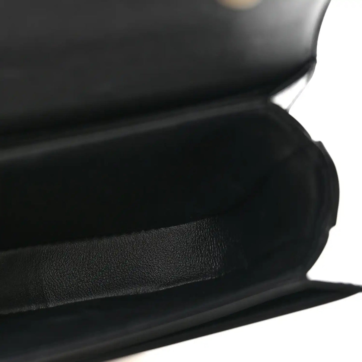 Black shiny mini crossbody bag, close-up of leather texture and curved front