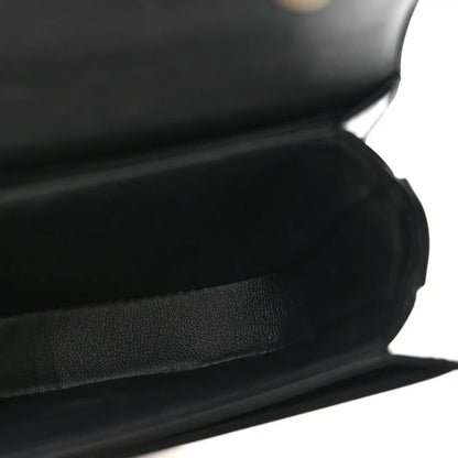 Black shiny mini crossbody bag, close-up of leather texture and curved front