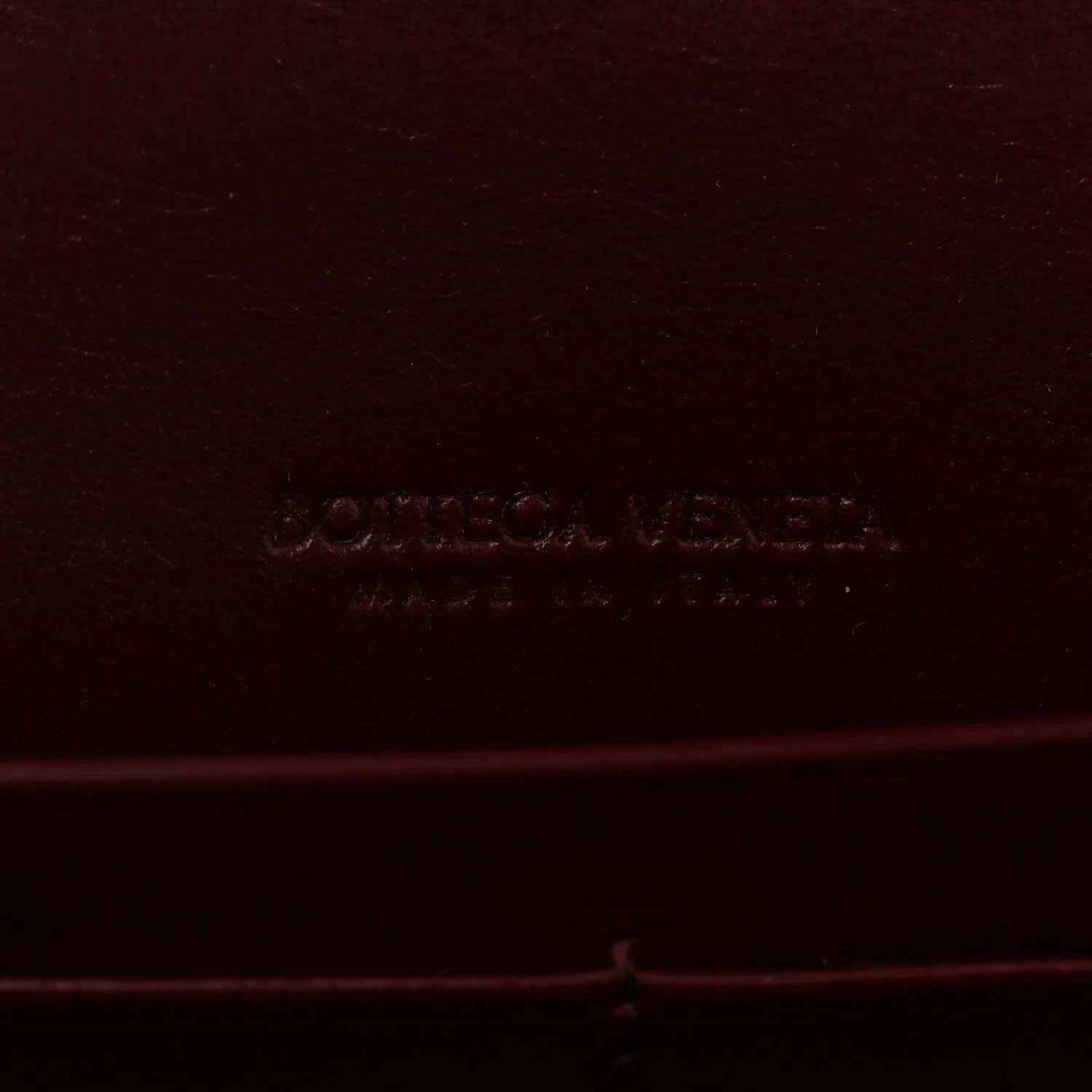 Burgundy leather clutch bag with embossed Bottega Veneta logo stamp