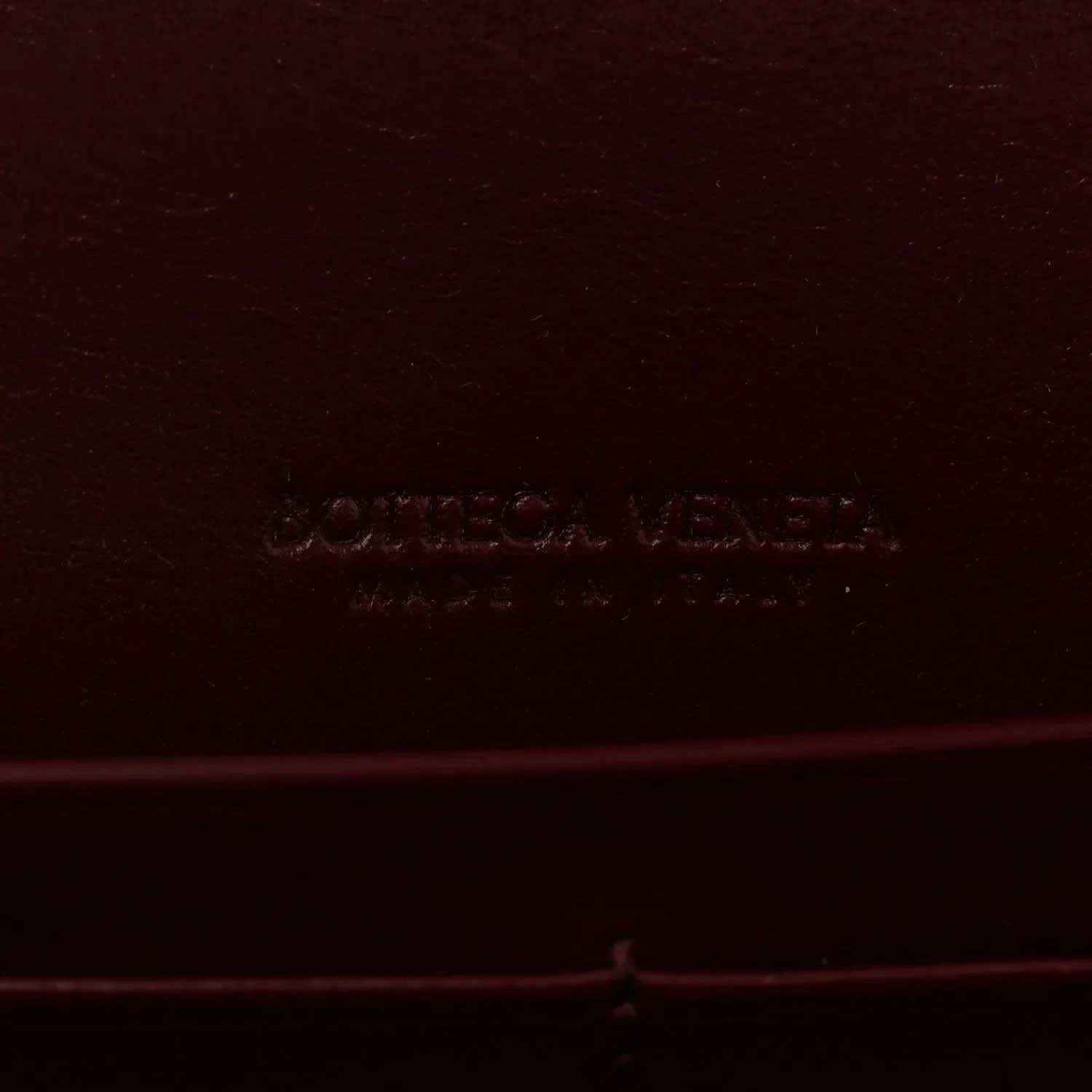 Burgundy leather clutch bag with embossed Bottega Veneta logo stamp