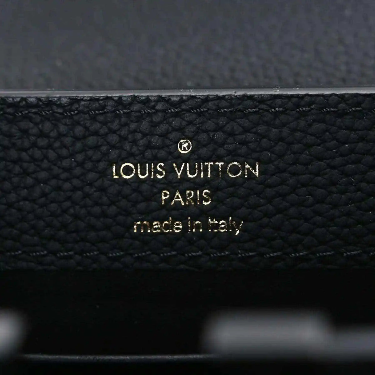 Louis Vuitton PARIS made in Italy stamp on black leather handbag.