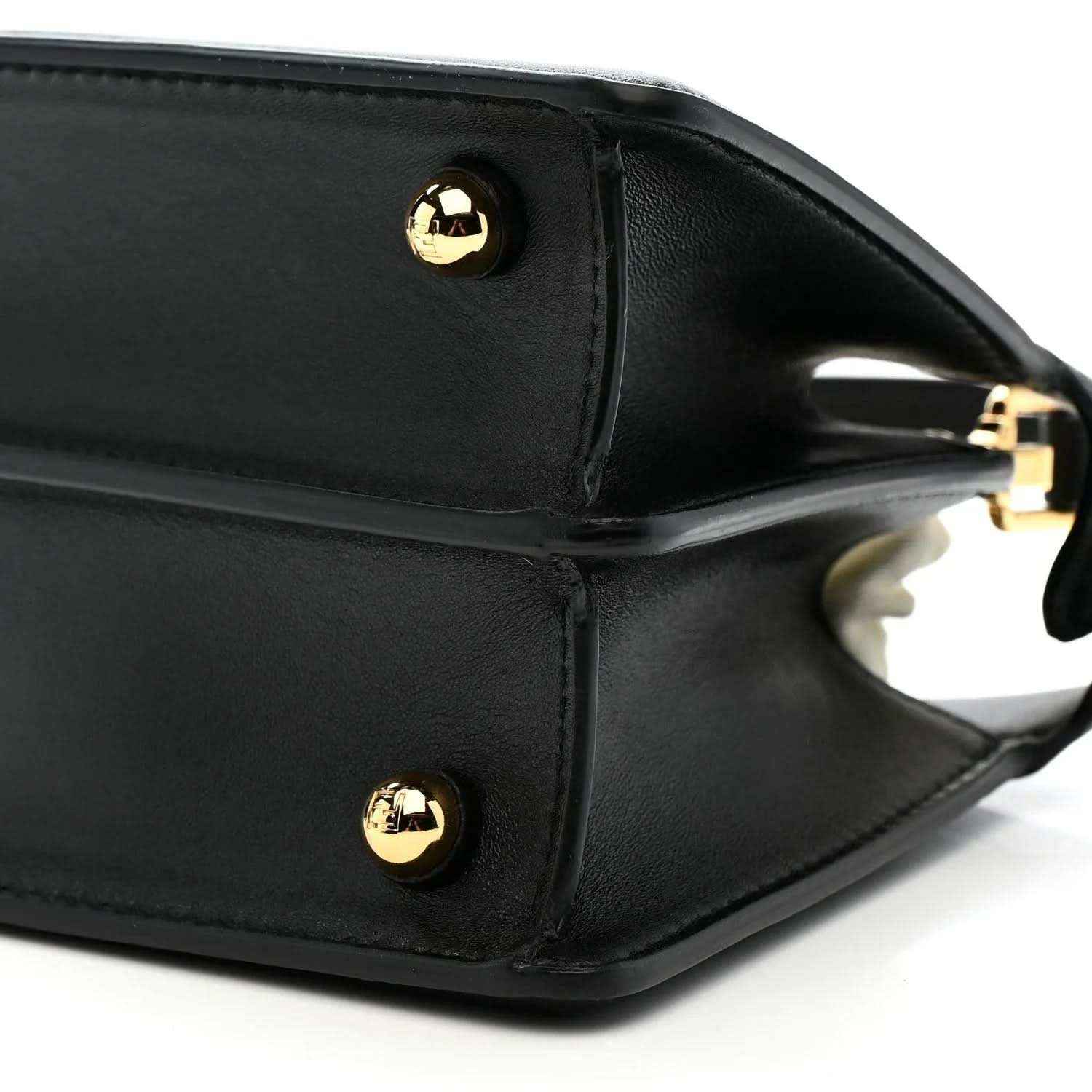 Black leather satchel side with gold-toned snap button and strap ring