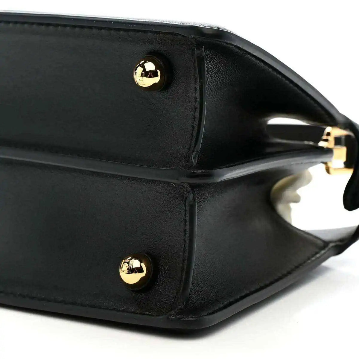 Black leather satchel side with gold-toned snap button and strap ring