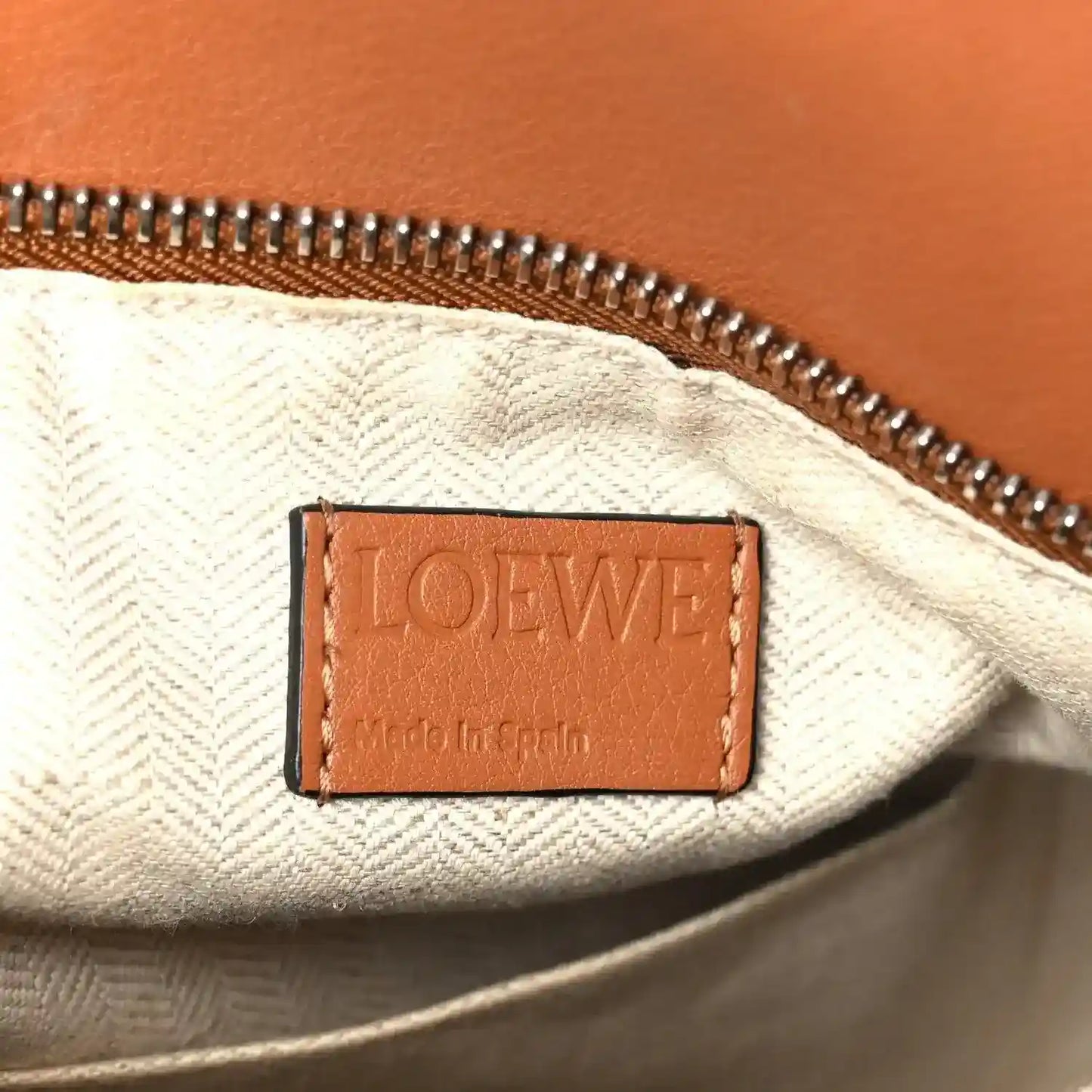 Loewe tan calfskin bag interior label with "LOEWE" text and zipper trim