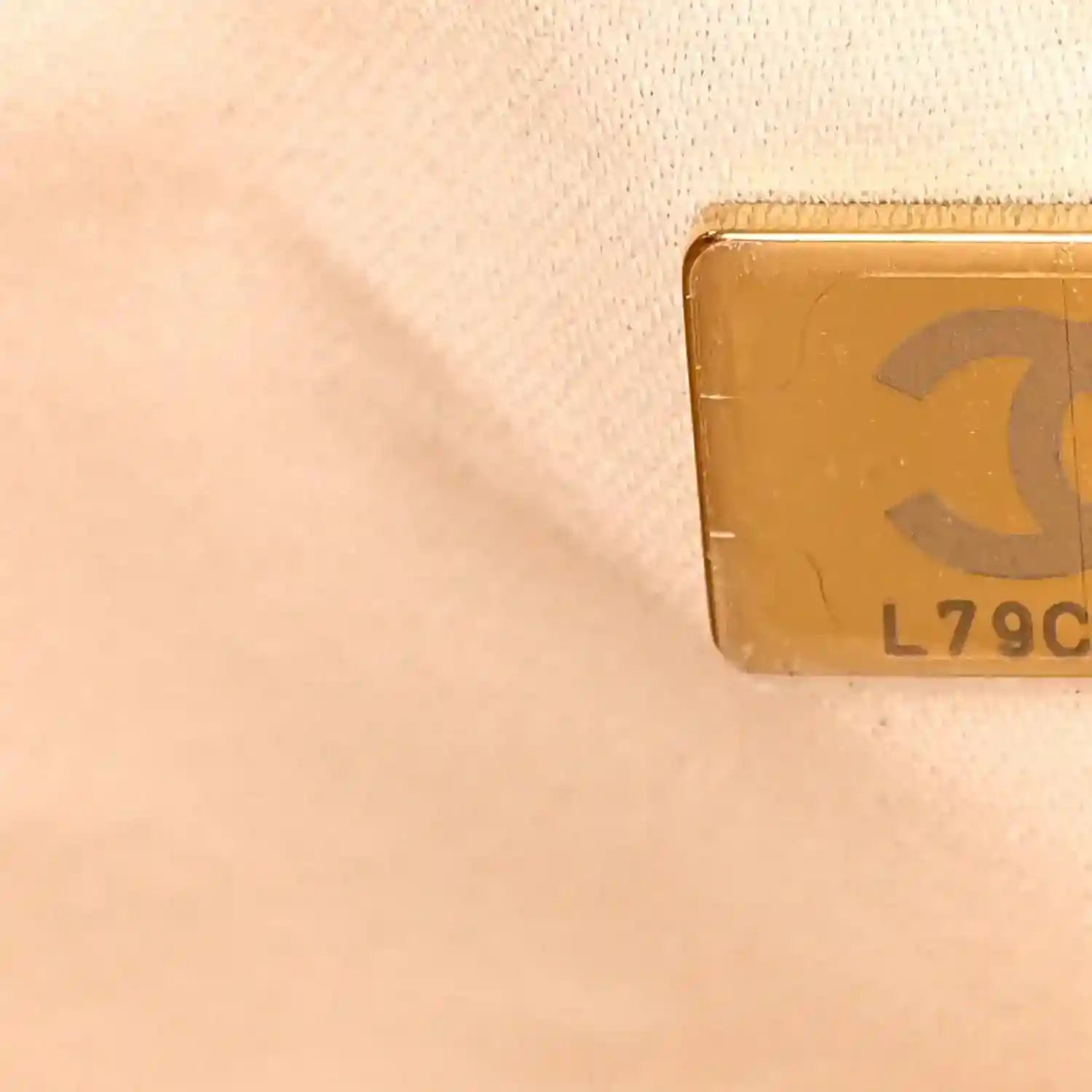 Light beige leather handbag with stamped code on metal plate