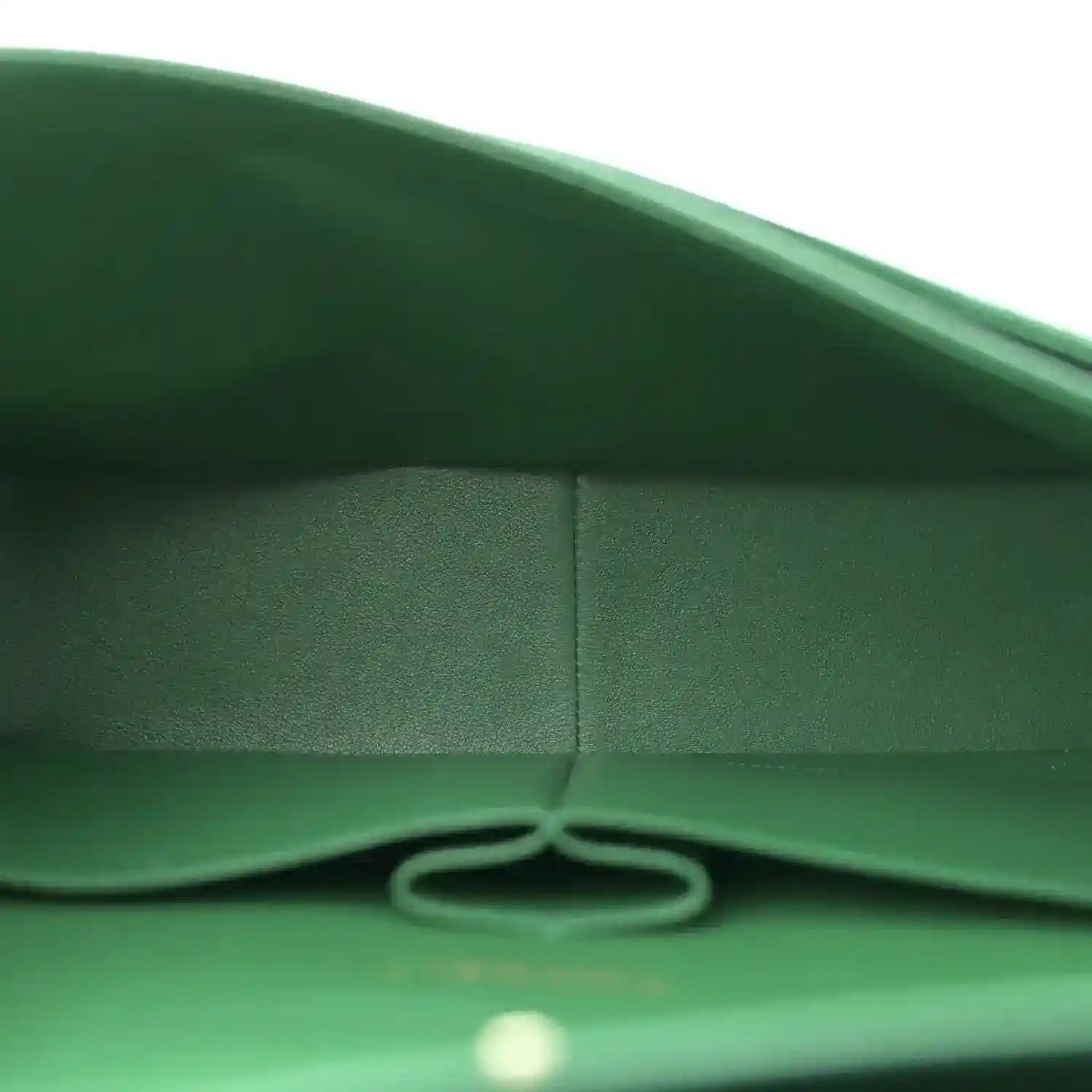 Green leather bag interior edge with stitching and metal ring detail.