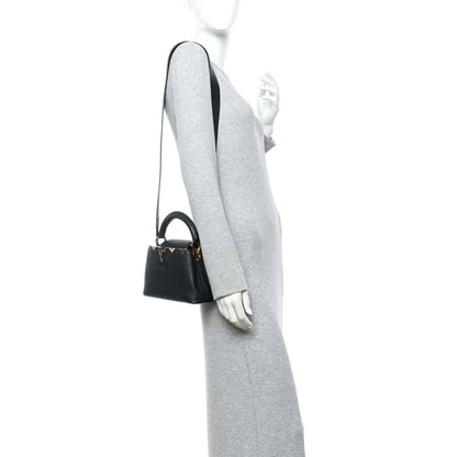 Black mini handbag on shoulder with crossbody strap and small gold hardware