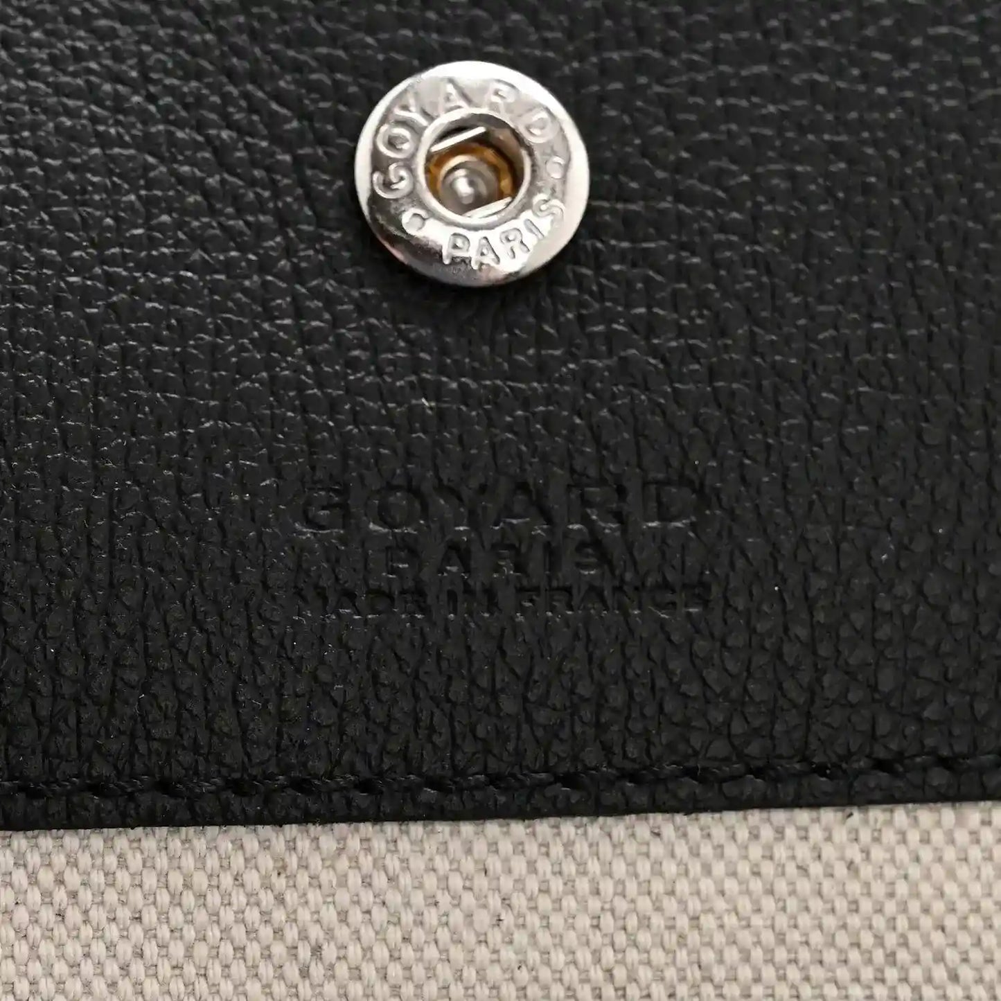 Goyard hobo bag front snap button with silver-tone hardware on black textured canvas
