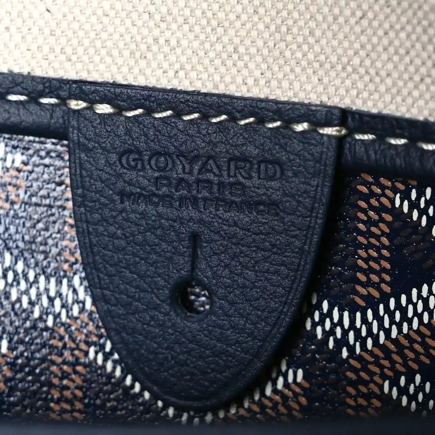 Goyardine tote bag corner patch with embossed logo and visible stitching