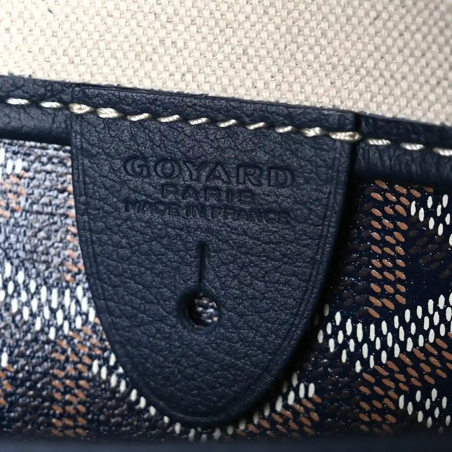 Goyardine tote bag corner patch with embossed logo and visible stitching