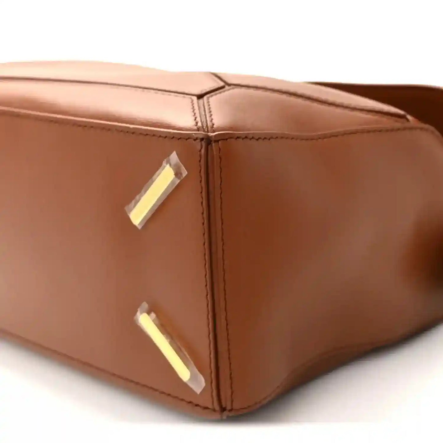 Pecan brown leather bag corner with gold-tone plaque and stitched edge