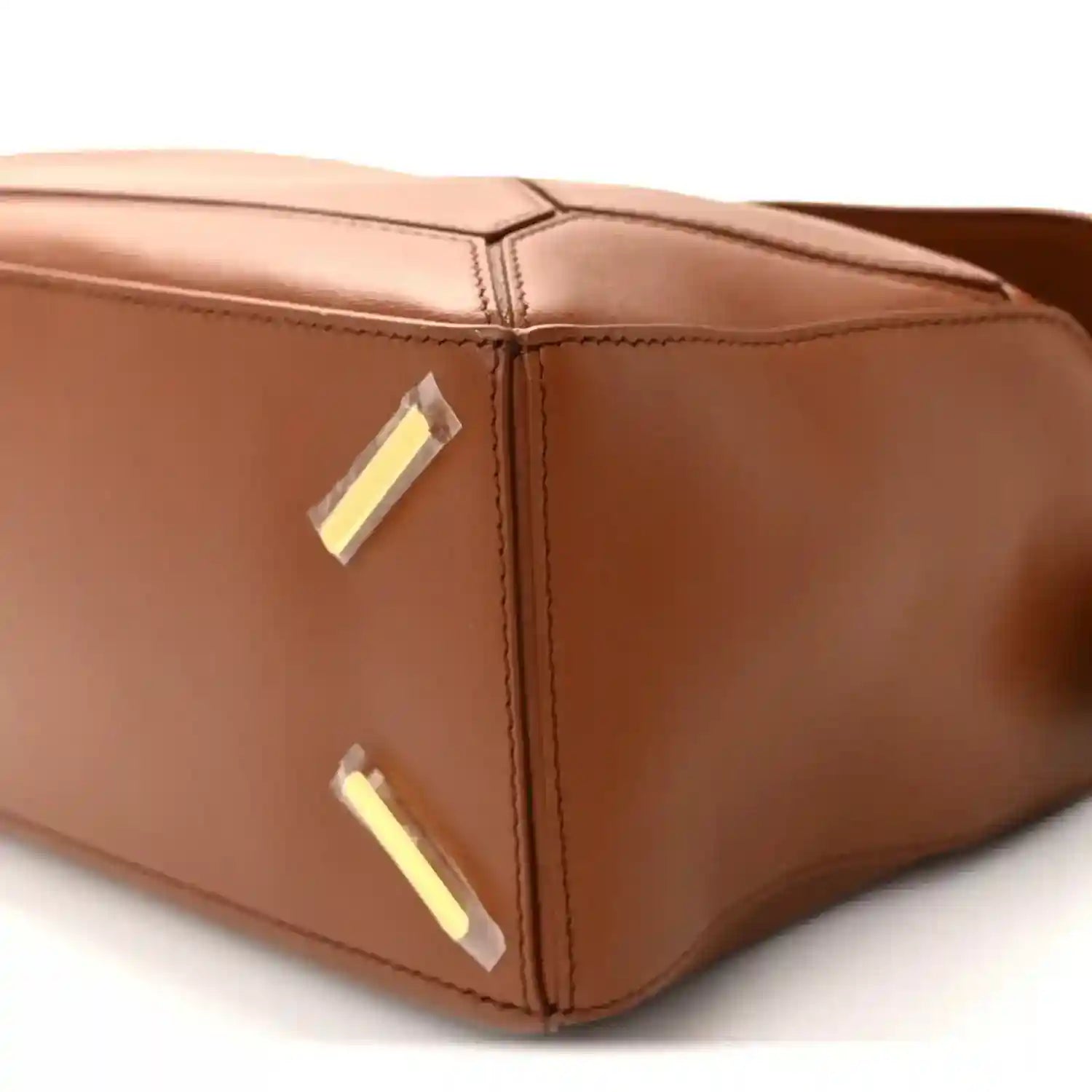 Pecan brown leather bag corner with gold-tone plaque and stitched edge