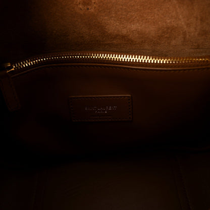 Tan leather interior pocket with stitched branding patch near gold zipper