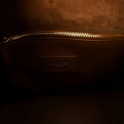 Tan leather interior pocket with stitched branding patch near gold zipper
