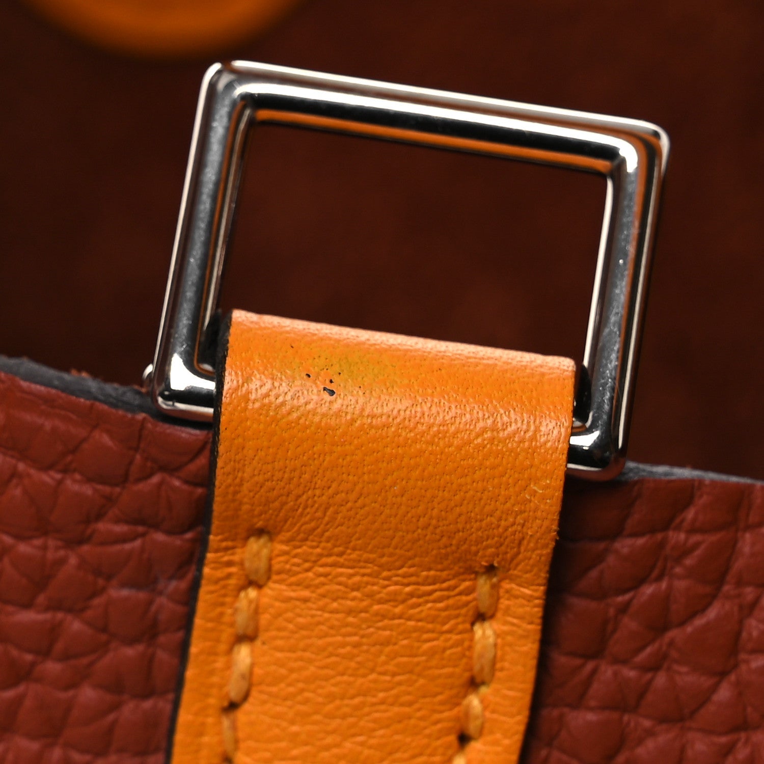 Leather tote with copper-orange handle strap and silver metal top handle hardware