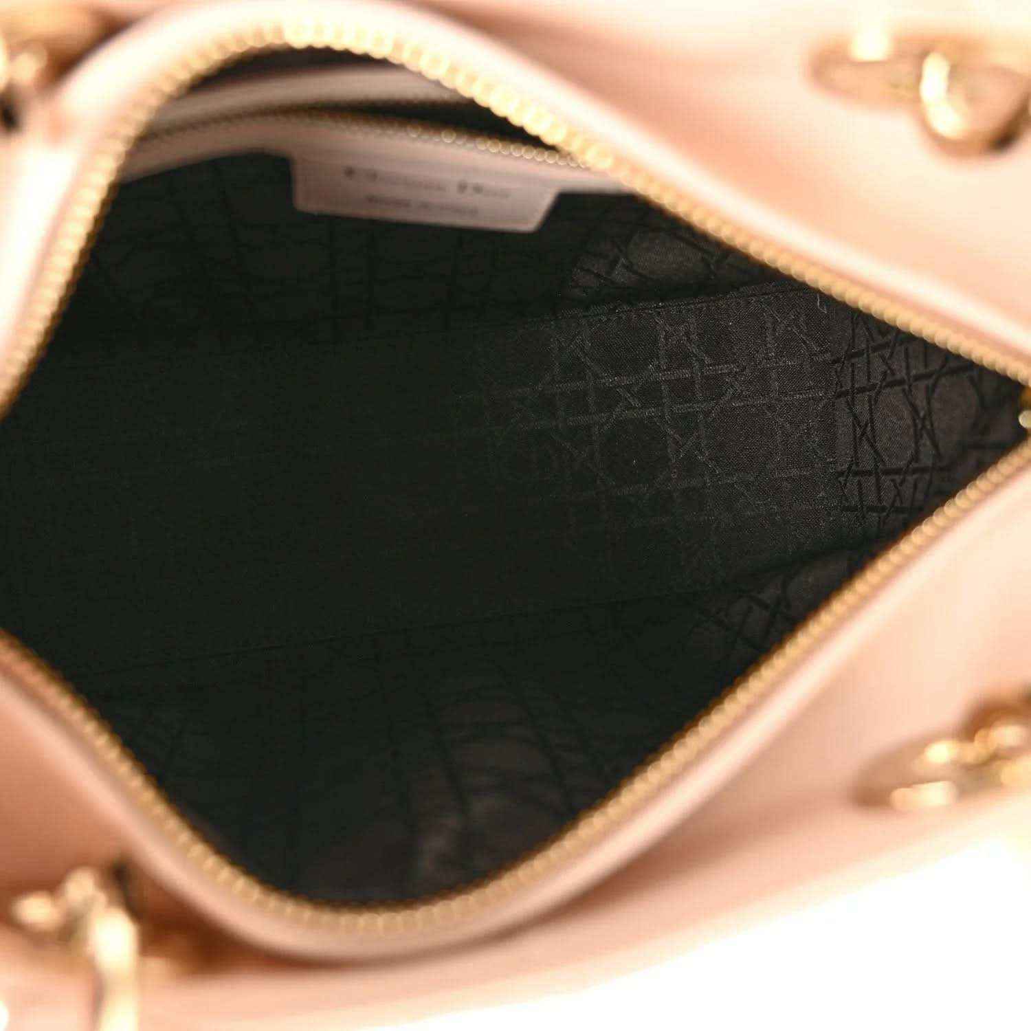 Dark fabric-lined interior with gold-tone zipper at top opening of powder pink bag.