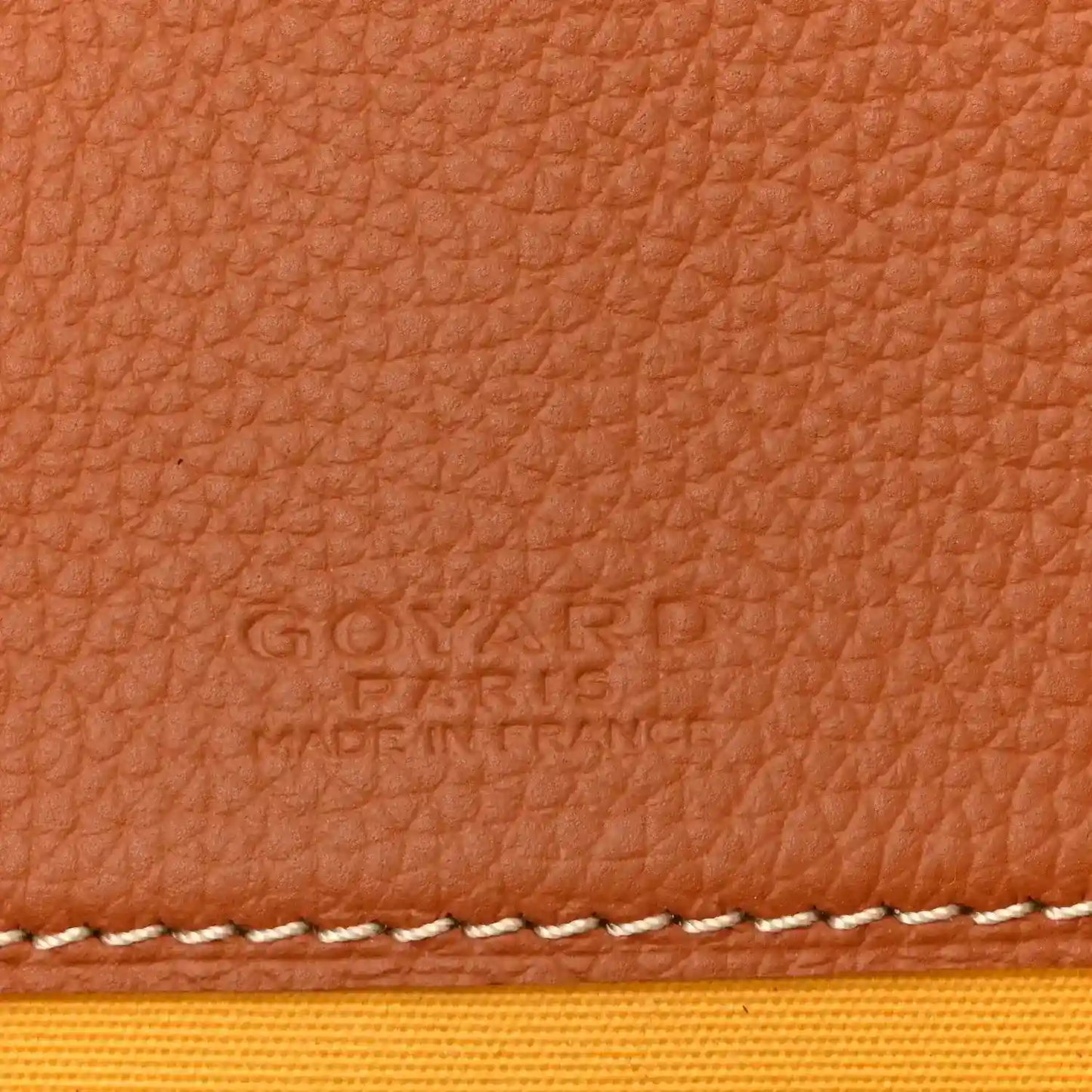 Tan leather panel with embossed brand text and white contrast stitching