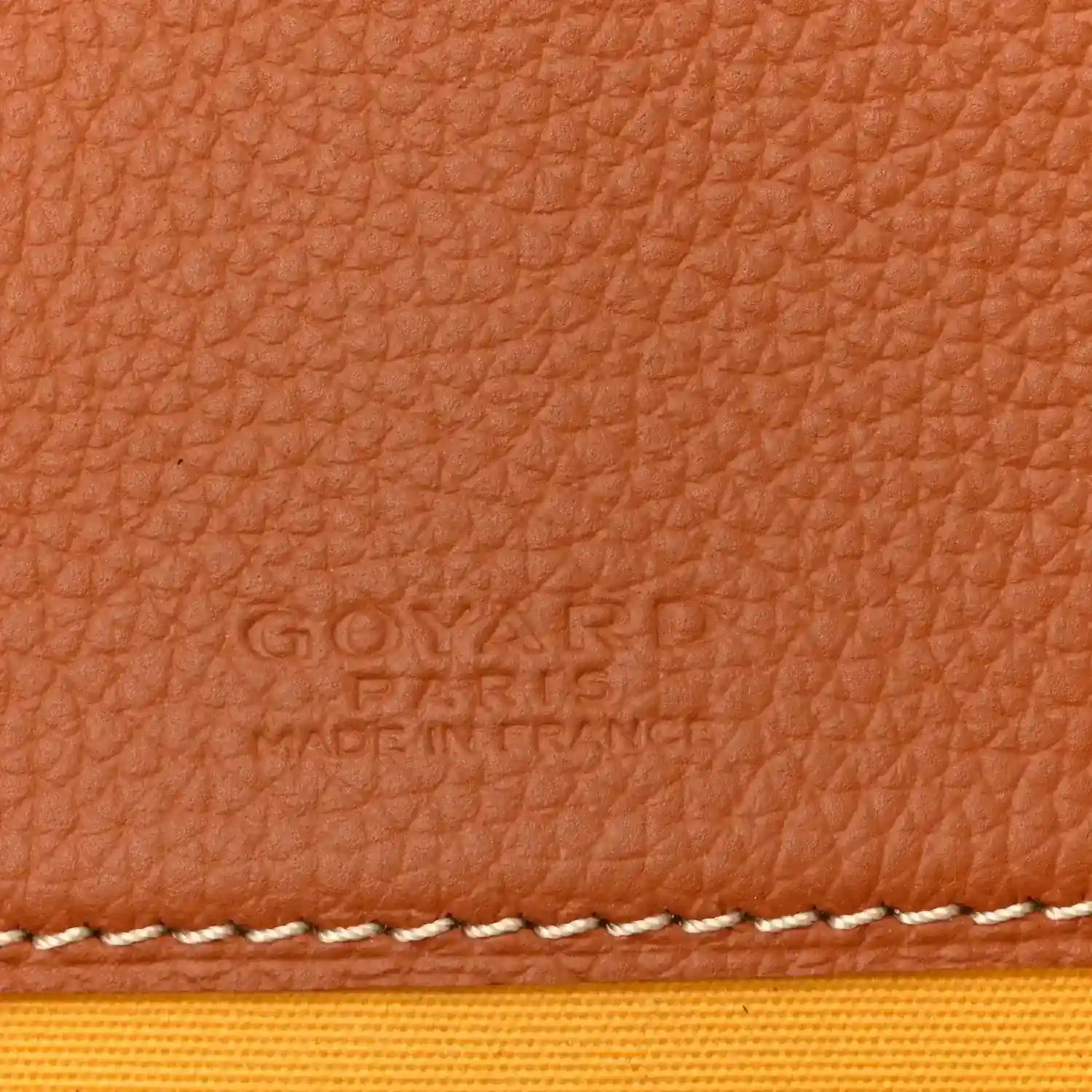 Tan leather panel with embossed brand text and white contrast stitching