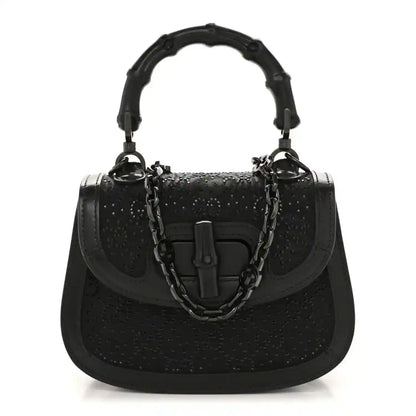 Black mini handbag with bamboo-style top handle and chain strap, textured with rhinestone sheen.