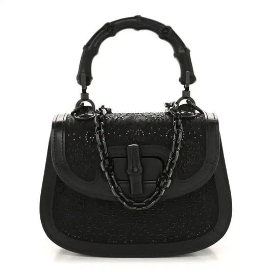 Black mini handbag with bamboo-style top handle and chain strap, textured with rhinestone sheen.