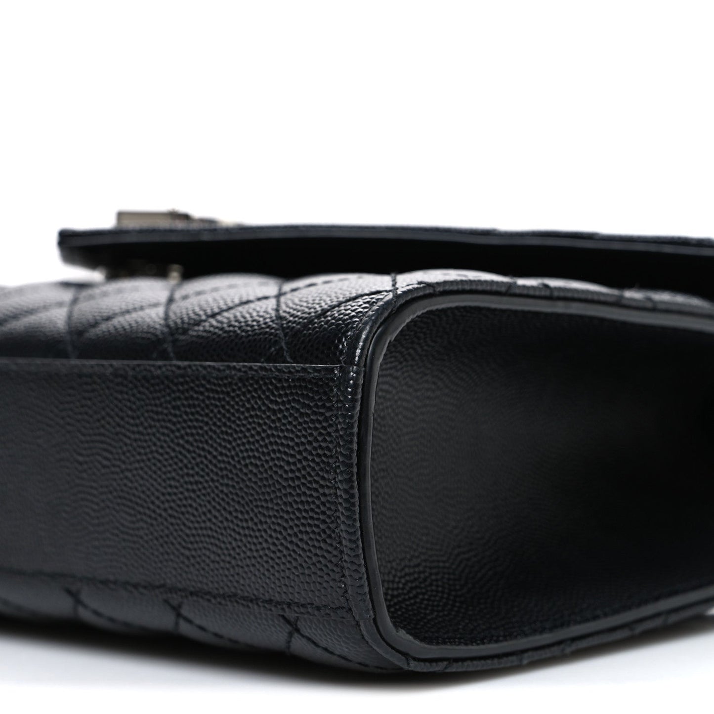 Black quilted leather satchel side edge with rounded corner and smooth border