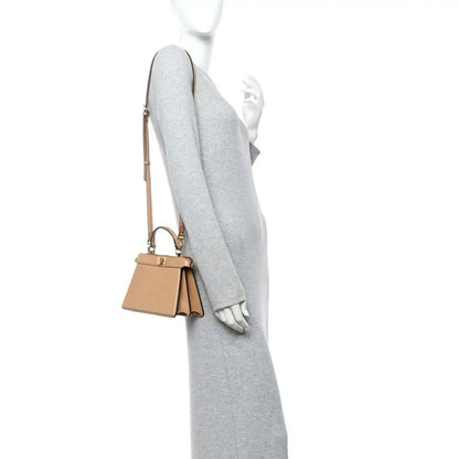 Tan mini satchel worn on shoulder with short strap and gold-tone hardware