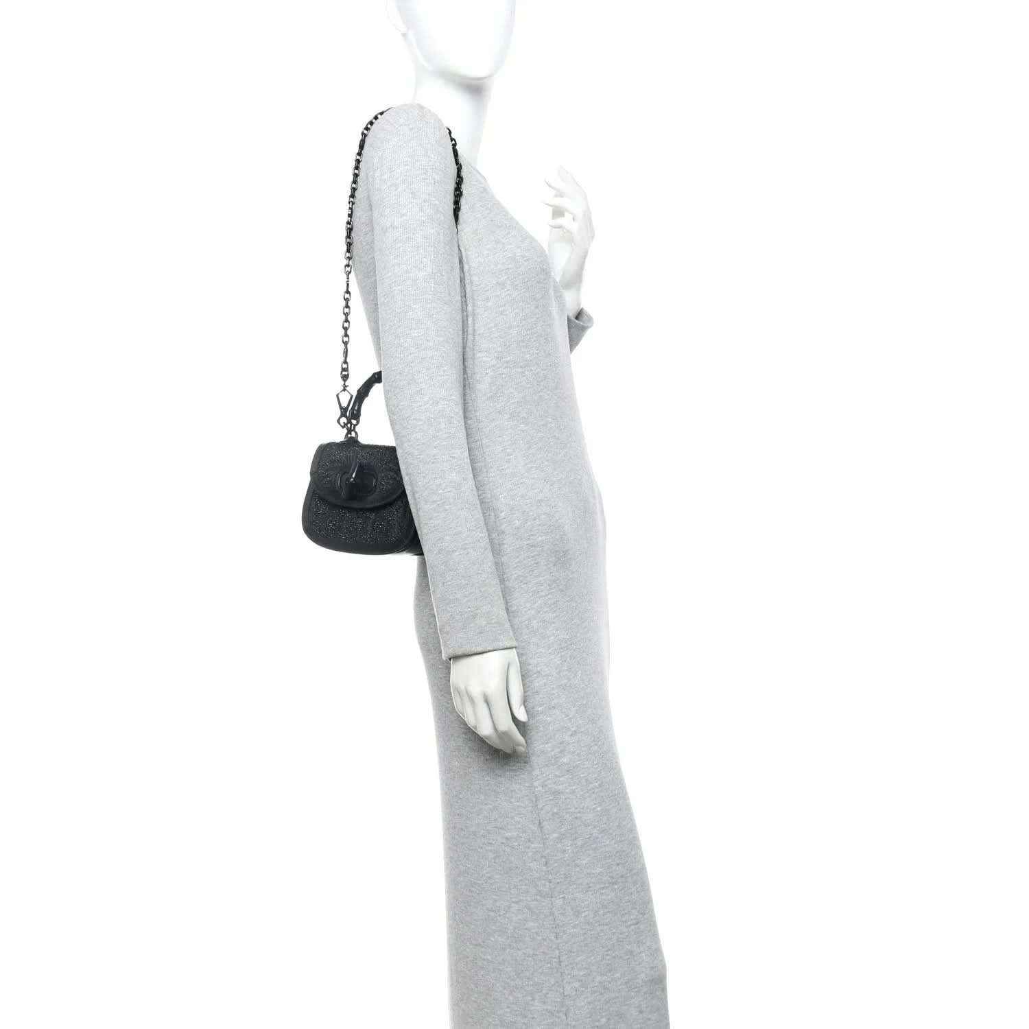 Black mini handbag on a person, with short chain strap and bamboo-style handle.