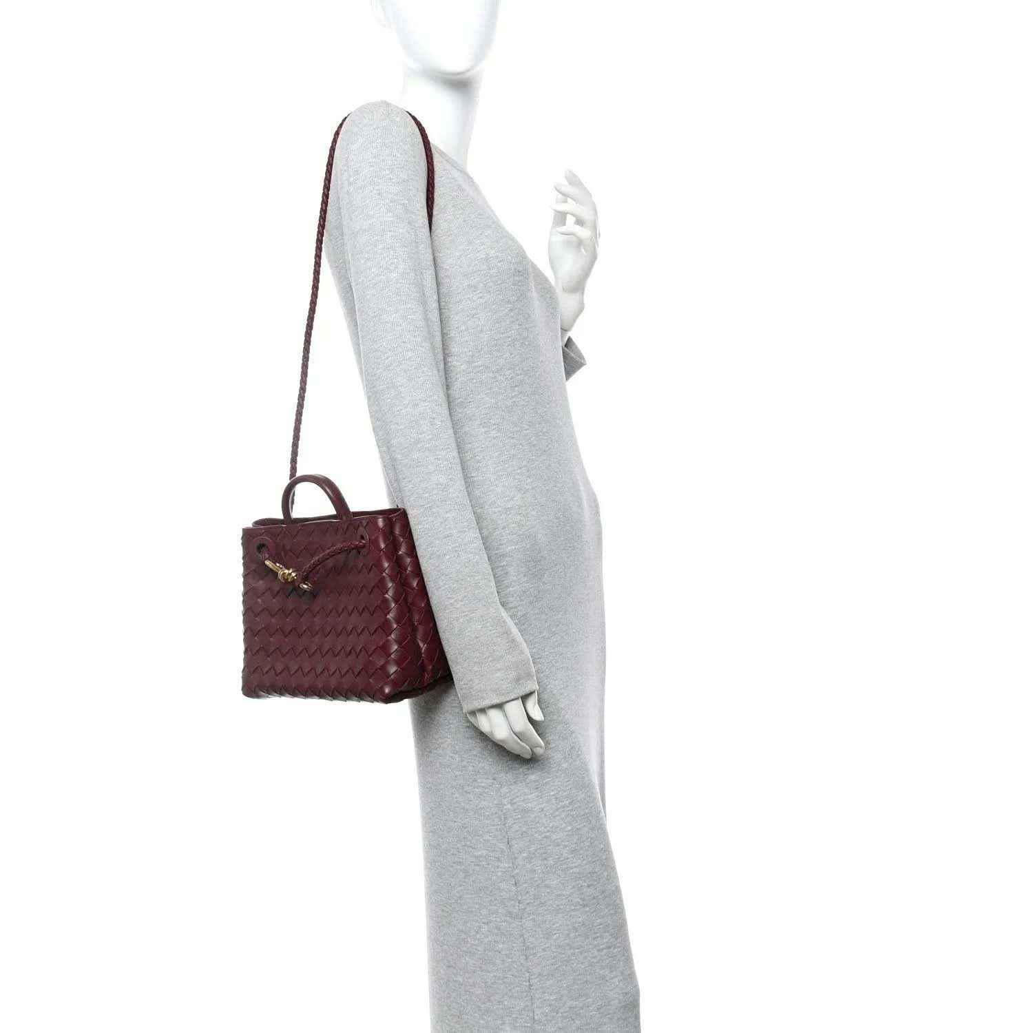 Small burgundy intrecciato leather shoulder bag worn crossbody by a mannequin.
