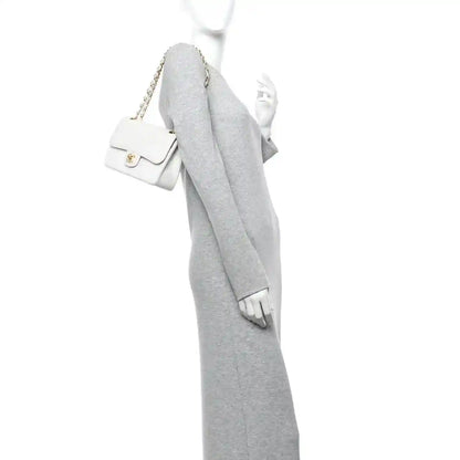 White leather mini shoulder bag with gold chain strap and flap, worn crossbody