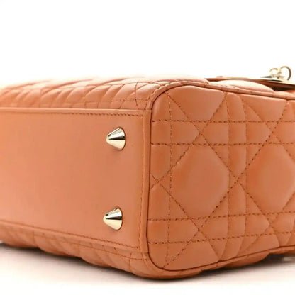 Front side close-up of orange quilted Lady Dior tote with two gold snap studs