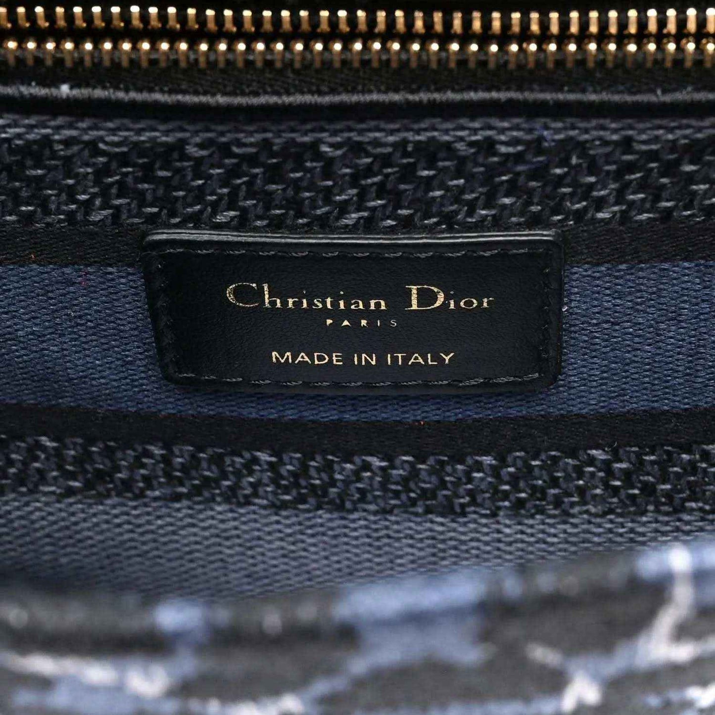 Christian Dior canvas handbag with leather logo tag reading “Christian Dior”