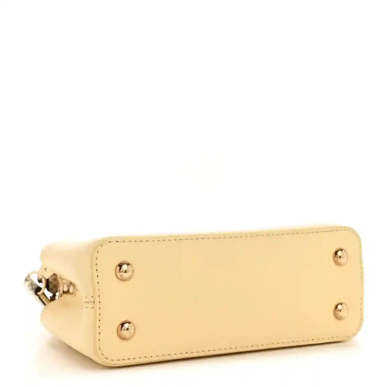 Cream mini handbag bottom corner with metal studs and side clasp hardware.