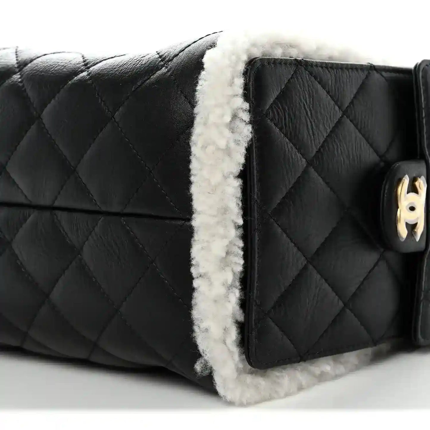 Black quilted handbag with white shearling trim and gold-tone turn-lock detail