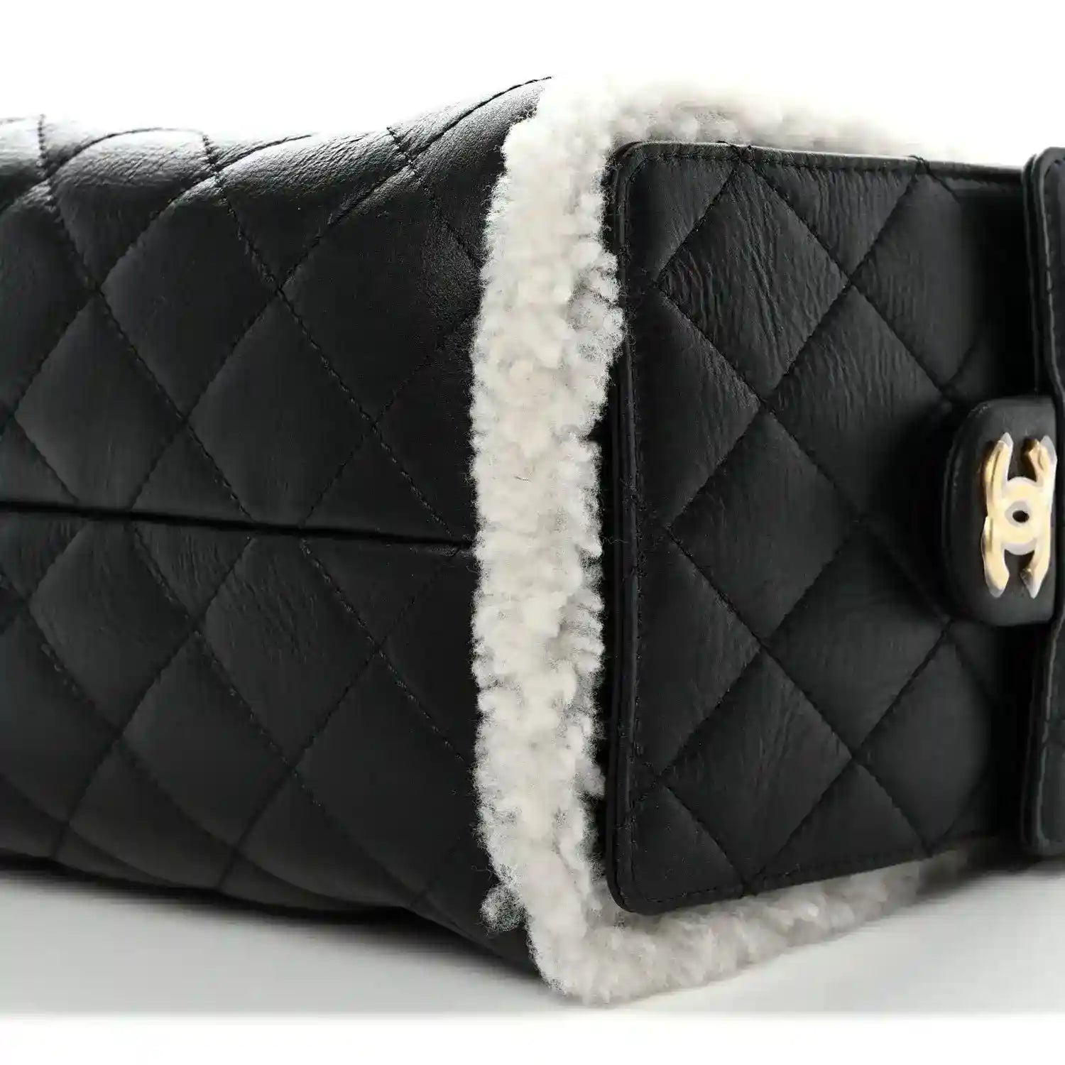Black quilted handbag with white shearling trim and gold-tone turn-lock detail