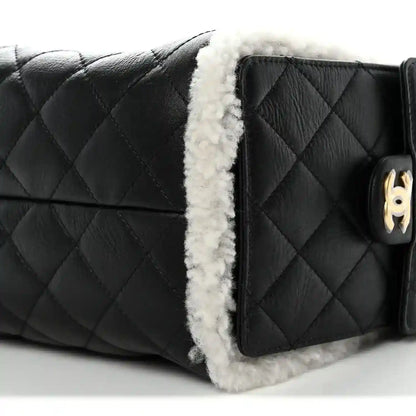 Black quilted handbag with white shearling trim and gold-tone turn-lock detail